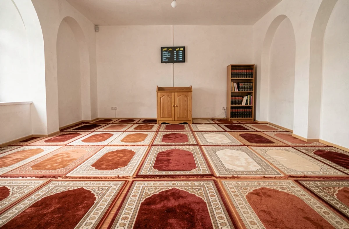 Intérieur d'une salle de prière avec tableau des horaires affiché dans une mosquée de Neuilly-sur-Marne